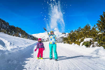 Mother and daughter, family, throwing snow powder up to the air, andorra, pyrenees