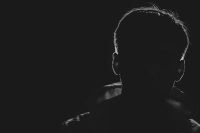 Side view of man looking away against black background