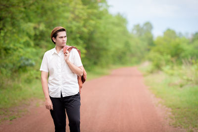Young woman standing on road against trees