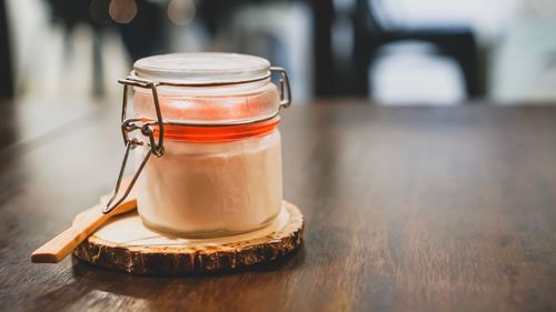 Close-up of strawberry pudding in glass jar on wooden table 