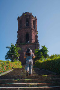 Rear view of woman by building against sky