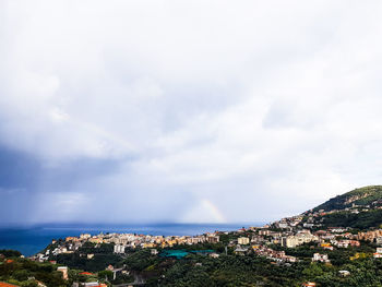 Aerial view of city by sea against sky