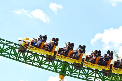 Low angle view of people sitting on amusement park