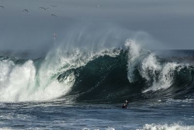 Man surfing in sea against sky