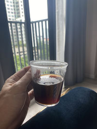 Person holding glass of window