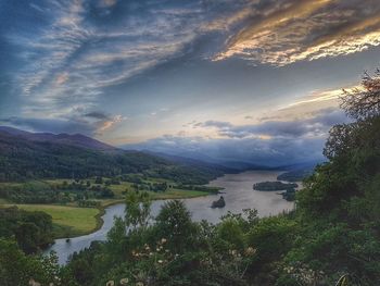 Scenic view of river by mountains against sky