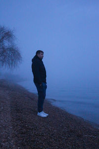 Side view of man standing on land against sky