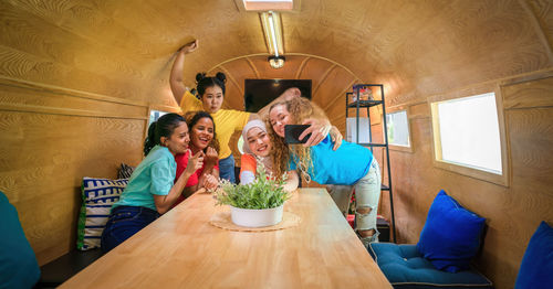 Woman taking selfie with friends on table in motor home