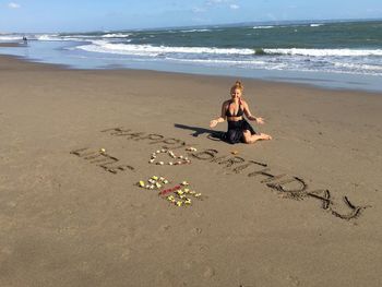 Woman by text at sandy beach on sunny day