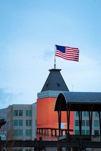 American flag on top of building against blue sky