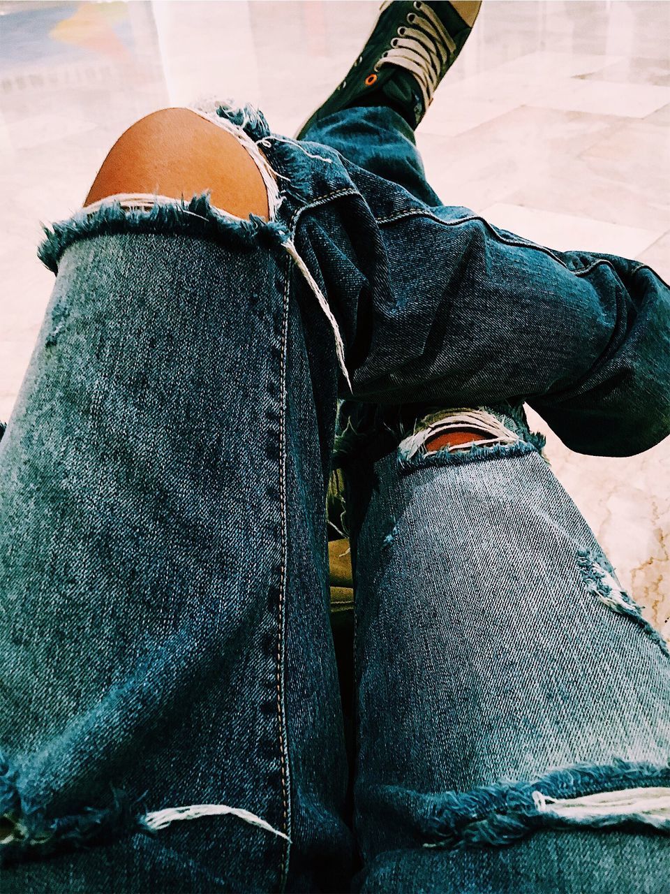 one person, jeans, human leg, casual clothing, real people, low section, human body part, lifestyles, body part, shoe, leisure activity, denim, personal perspective, textile, day, men, sitting, torn, relaxation, human foot, human limb, leather