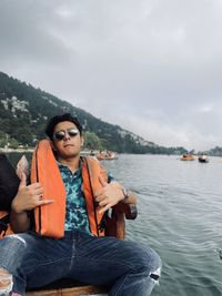 Portrait of young man sitting on a boat on a lake 