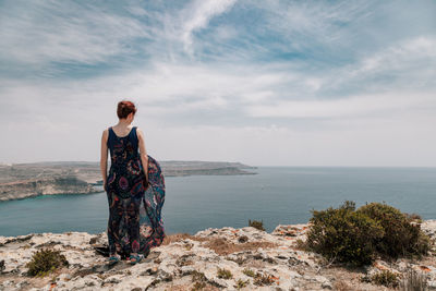 Rear view of man standing by sea against sky