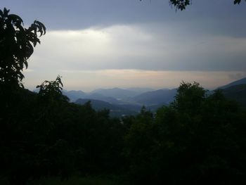 Silhouette trees and mountains against sky