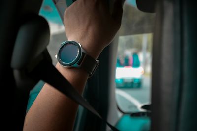 Cropped image of woman wearing wristwatch in car