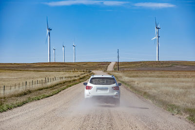 Wind turbines in colorado against blue sky with car