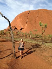 Full length of woman on landscape by tree trunk against sky