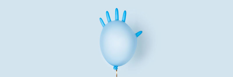 Festive balloon inflated from blue medical glove. web banner with central decorative element.