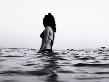 Woman wearing bikini in sea against clear sky