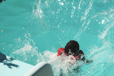 High angle view of boy enjoying slide in swimming pool