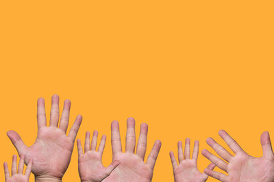 Close-up of hands against orange wall