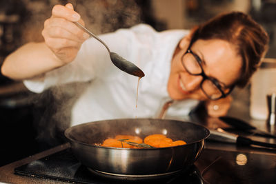 Female chef is checking cooked apricot confiture