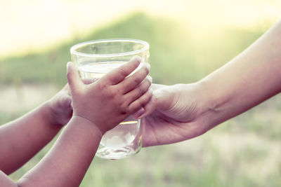 Cropped image of mother giving drinking water to kid