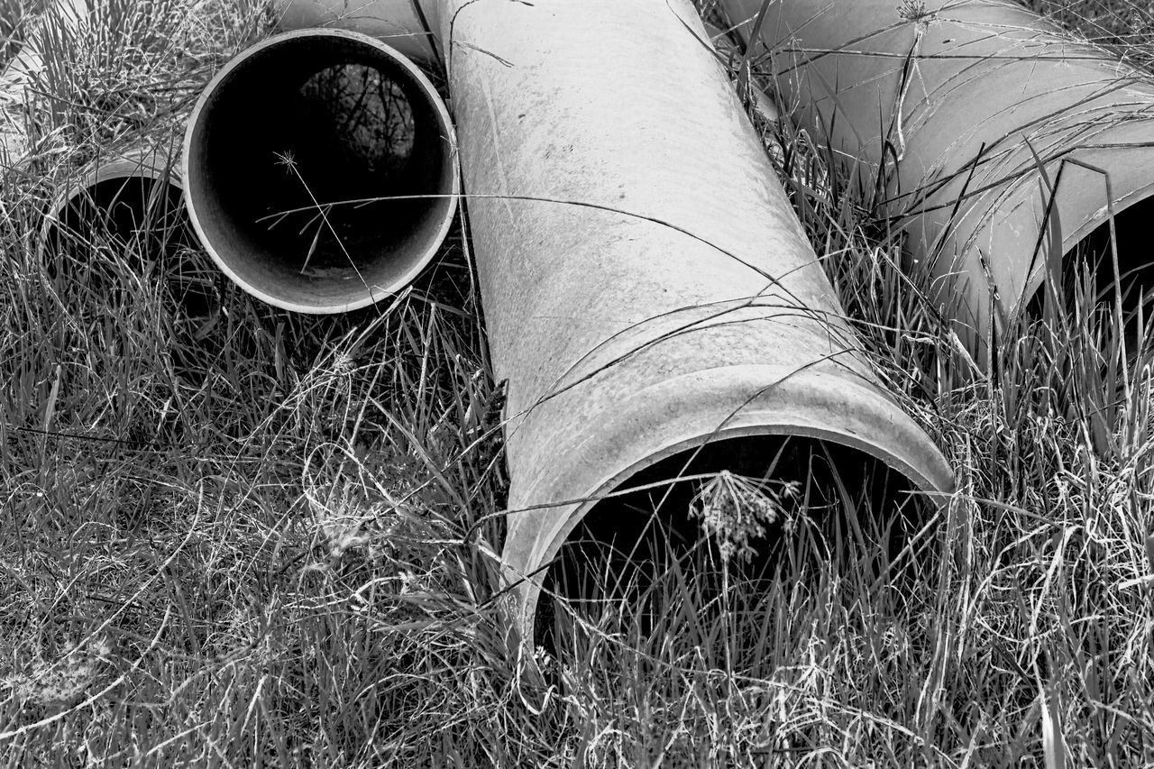 LOW SECTION OF PERSON STANDING ON FIELD BY ABANDONED PIPE