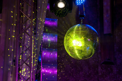 Low angle view of illuminated disco ball hanging at night