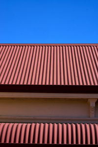 Low angle view of building roof against clear blue sky