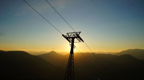 Silhouette electricity pylon against sky during sunset