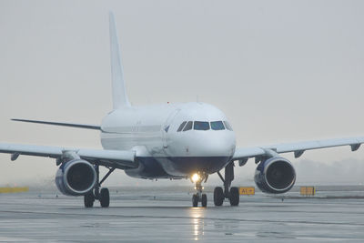 Airplane on airport runway against sky