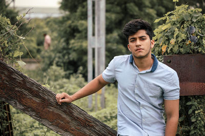 Portrait of young man standing against trees