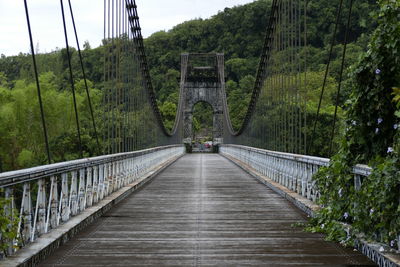 Footbridge amidst trees against sky