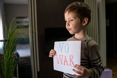 Cute boy with no war placard at home