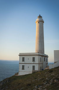 Lighthouse by sea against clear sky