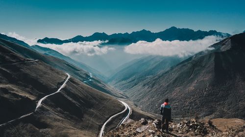 Rear view of man standing on mountain against sky