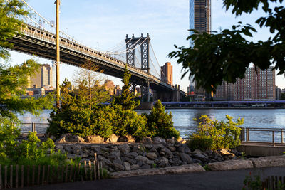 Bridge over river by buildings in city against sky