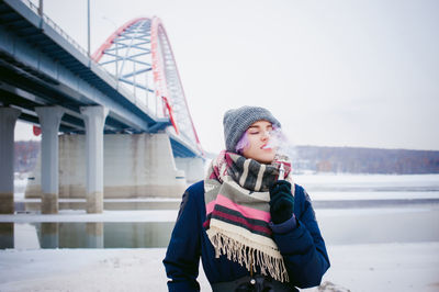 Happy young woman on snow covered bridge