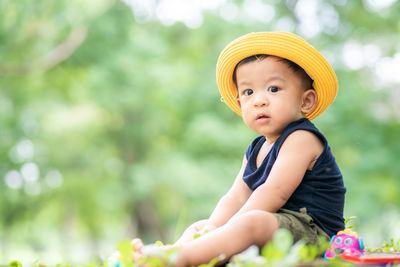 Portrait of cute boy wearing hat sitting outdoors