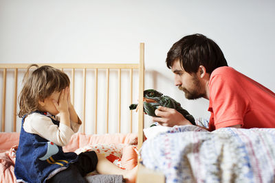 Father and daughter playing with toy at bed in home
