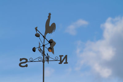 Low angle view of weather vane against blue sky