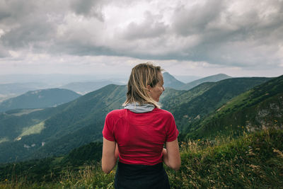 Rear view of woman standing on mountain against sky