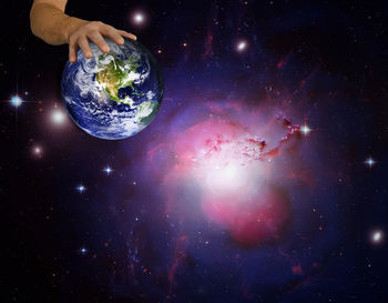 Digital composite image of hand against illuminated star field at night