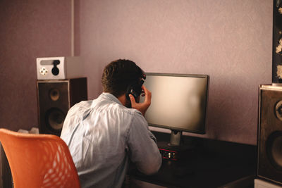 Concentrated man listening music on headphones sitting by computer