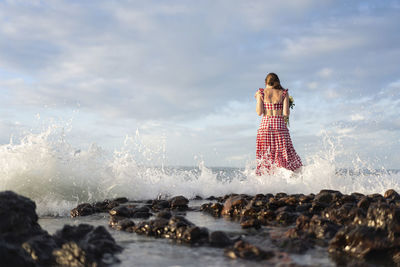 Woman looking at sea shore against sky