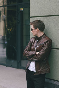 Young man looking at camera while standing against wall