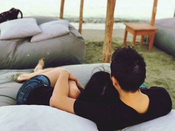 Rear view of couple relaxing on sofa at beach