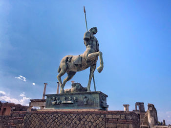 Low angle view of statue against building against sky