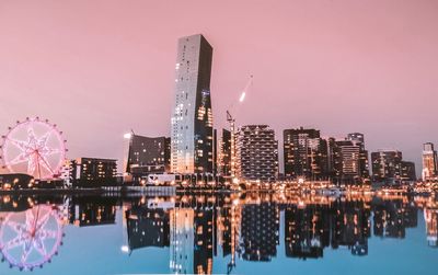 Reflection of illuminated buildings in city against sky